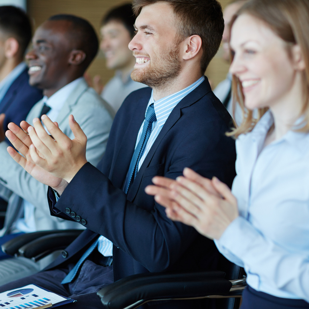 Mennesker som sitter på rader og applauderer.