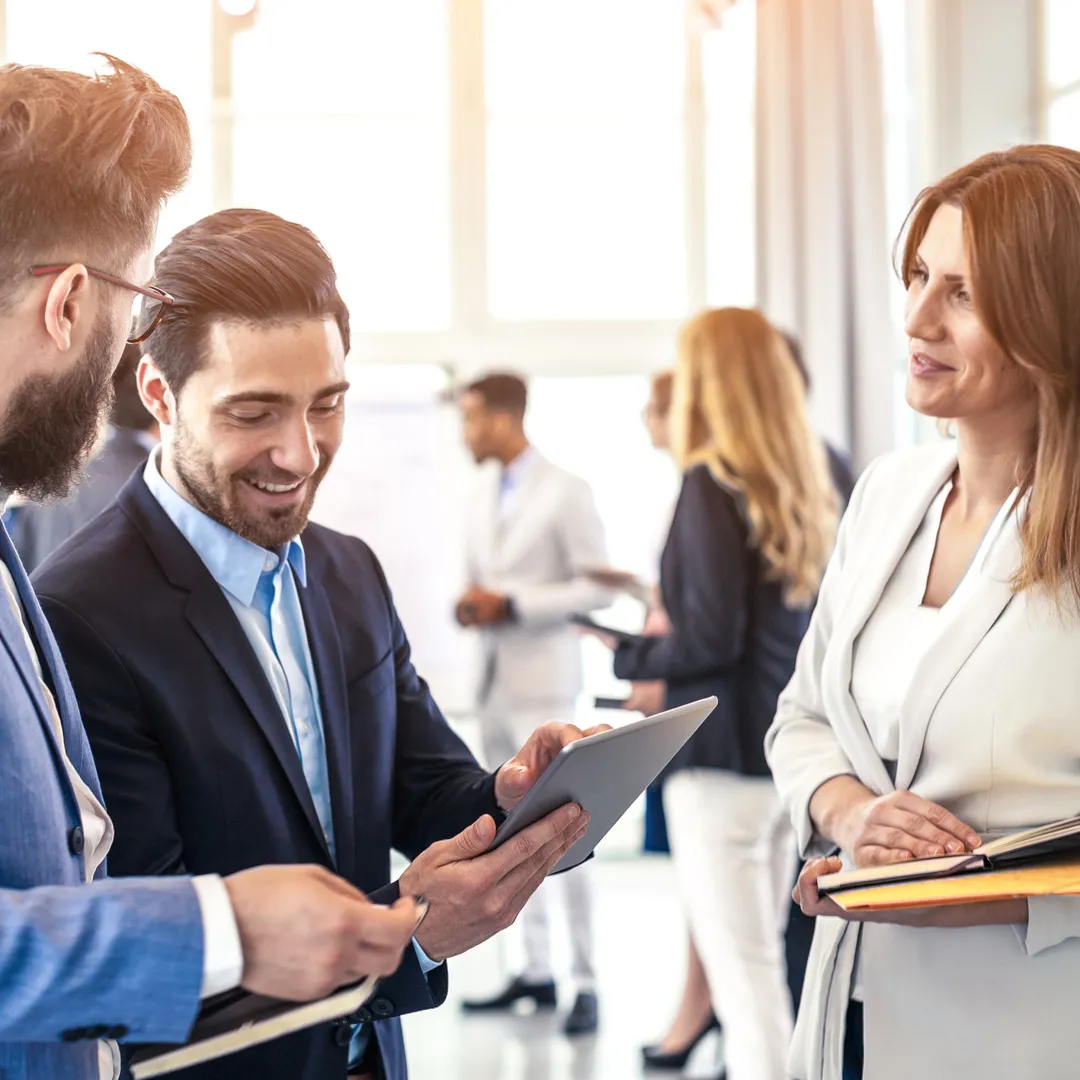 Bilde av mennesker i et møtelokale som står og snakker sammen 
