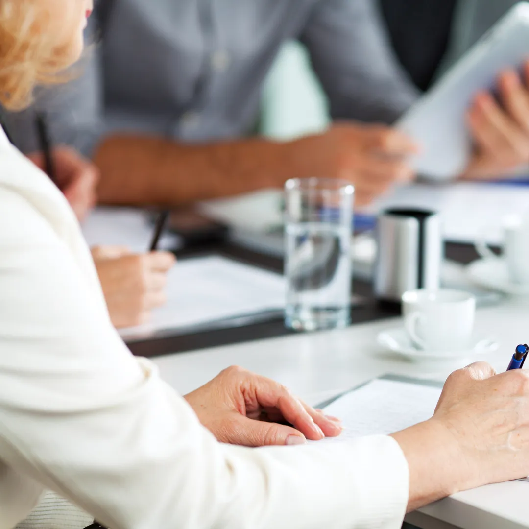 Bilde av et bord i møterom der du ser flere mennesker samlet