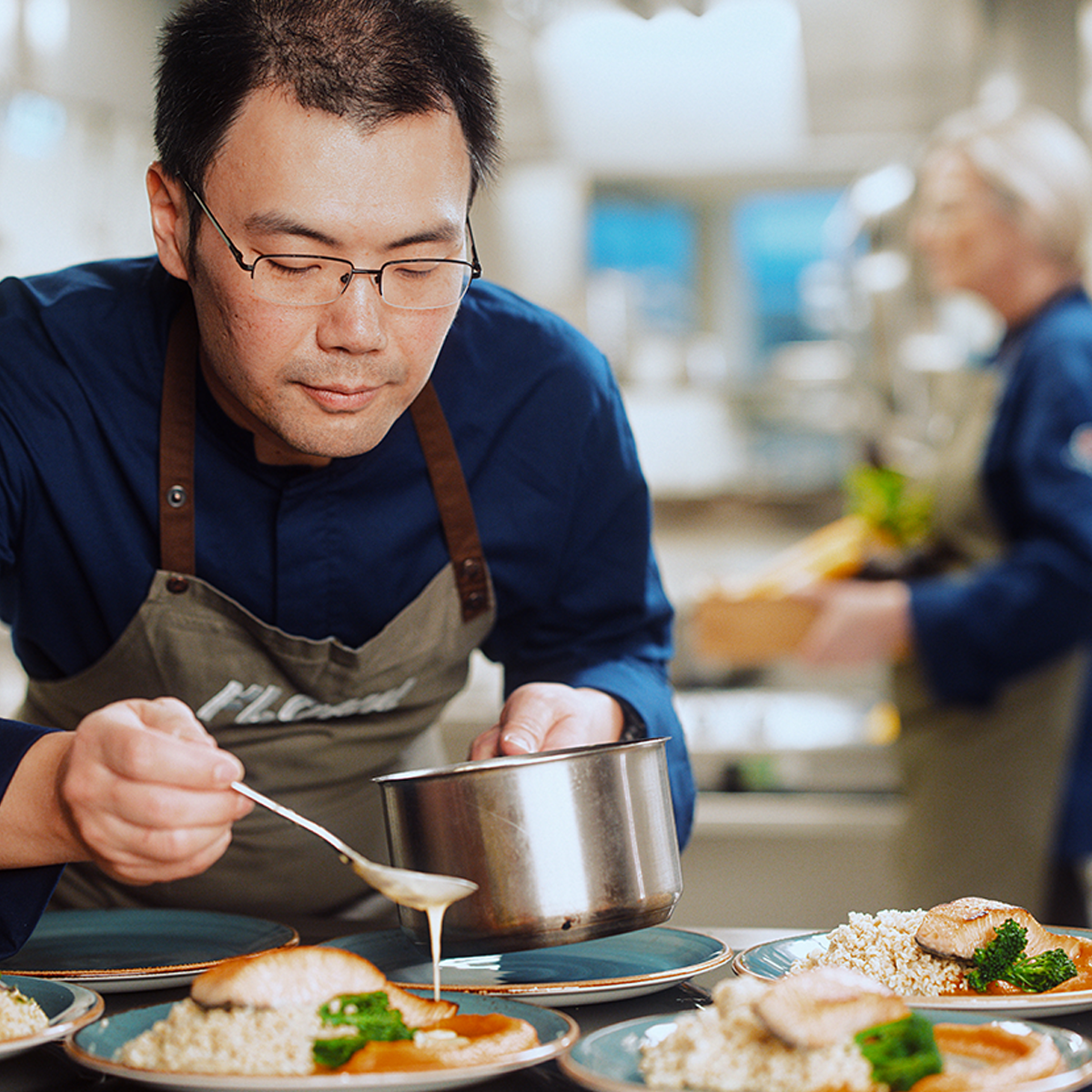 Mannlig kokk som heller saus over mat
